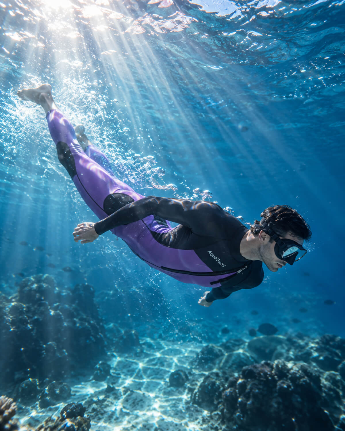Freediver swimming underwater in a purple wetsuit and dive mask