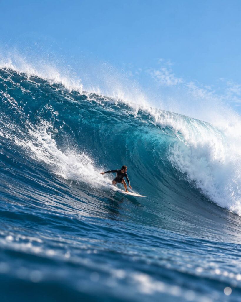 Surfer riding a large blue ocean wave